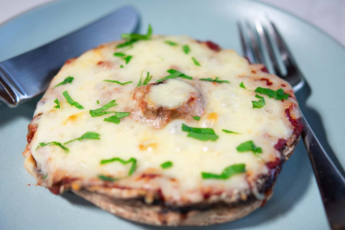 portabella mushroom pizza on a blue plate with fork and knife