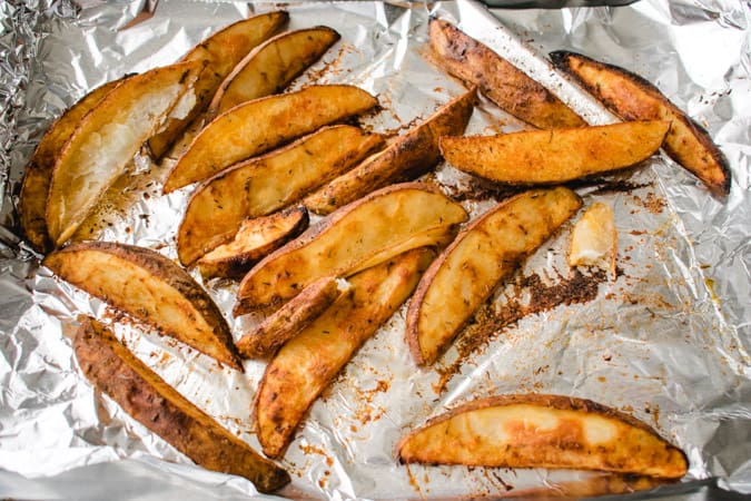 cooked potato wedges on a foil lined pan